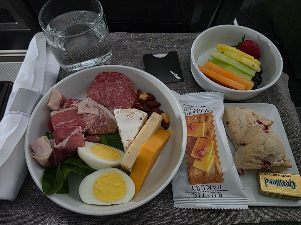 American Airlines first class charcuterie board featuring prosciutto, cheeses, almonds and egg — a surprising switch after a catering mix-up.