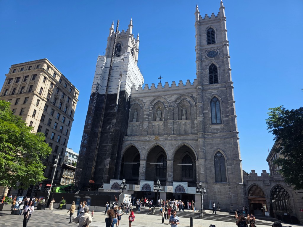 Notre-Dame Basilica of Montréal overlooking Place d'Armes on a sunny summer day in Old Montreal.